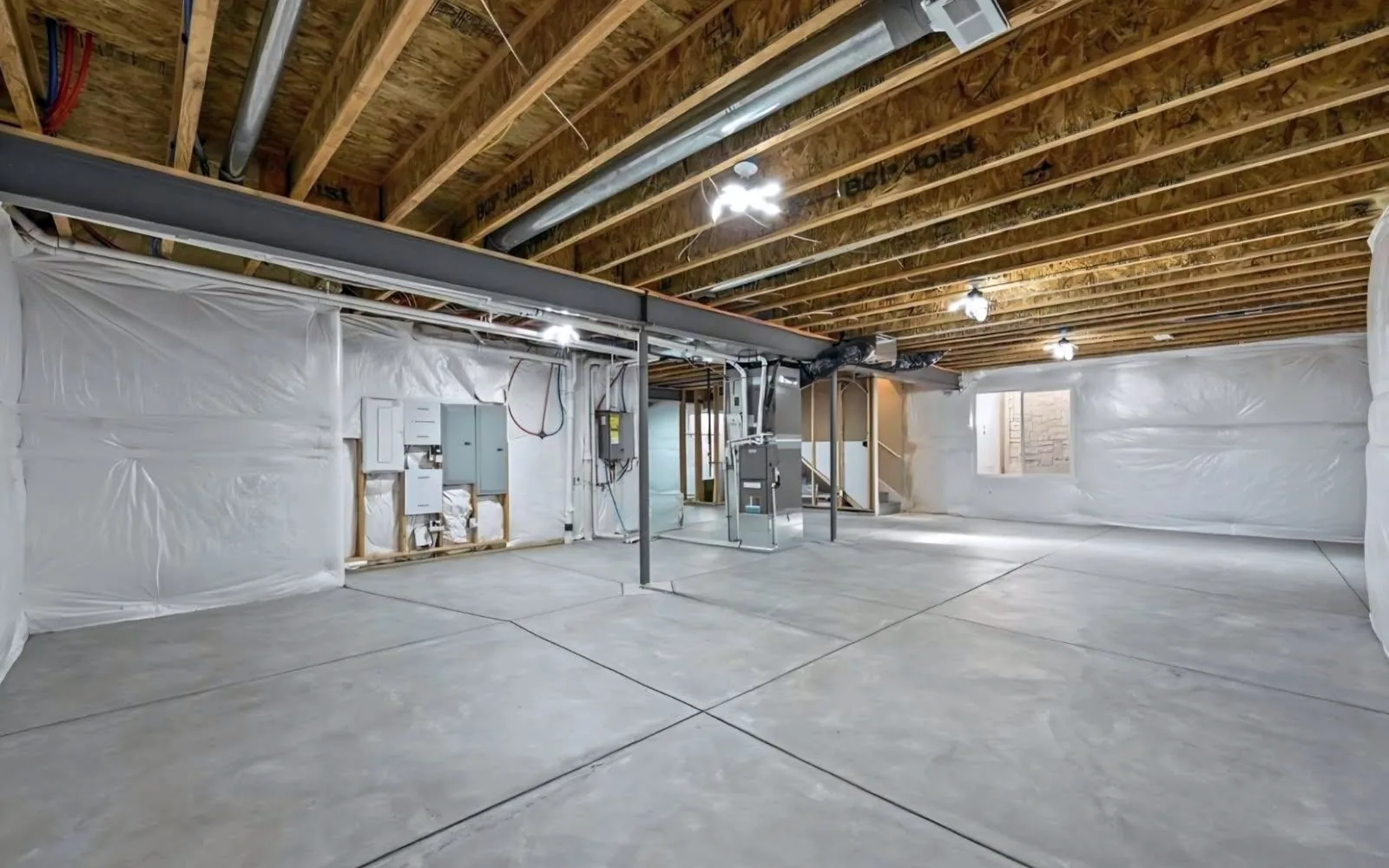Unfinished Colorado basement before renovation with exposed joists, ductwork and a bare concrete floor